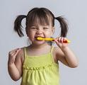 Toddler smiling while brushing her teeth