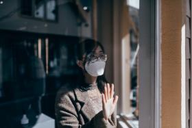 Woman wearing a mask looking out the window